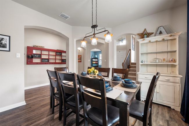 Dining space featuring arched walkways, dark wood-style flooring, and stairway | Image 10