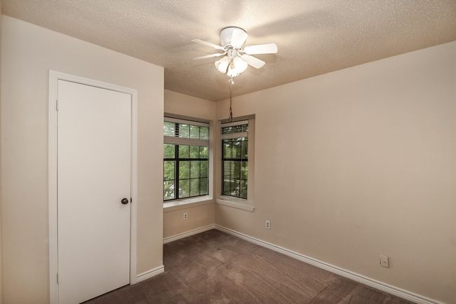 Spare room with a ceiling fan, dark carpet, and a textured ceiling | Image 15