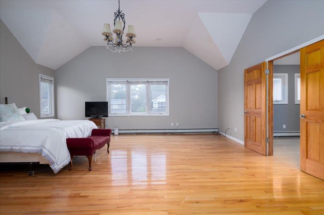 Bedroom featuring a baseboard heating unit, baseboard heating, multiple windows, a chandelier, and lofted ceiling | Image 24