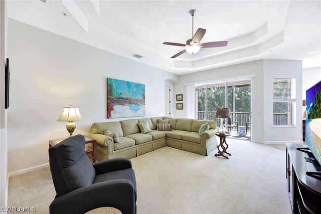 Living room with carpet floors, ceiling fan, and a raised ceiling | Image 7