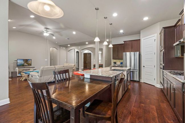 Dining room with arched walkways, dark wood-type flooring, a ceiling fan, recessed lighting, and lofted ceiling | Image 12
