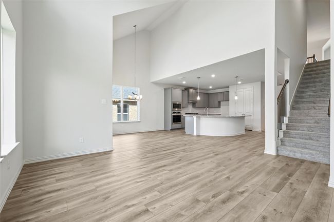 Unfurnished living room with light wood-style floors, stairway, high vaulted ceiling, and a chandelier | Image 15