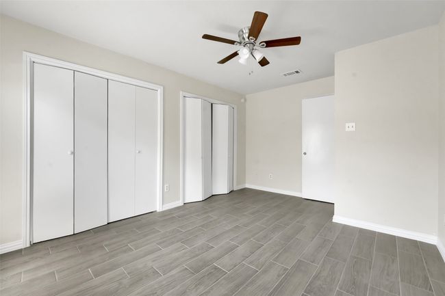 Unfurnished bedroom featuring multiple closets, wood finished floors, and ceiling fan | Image 14