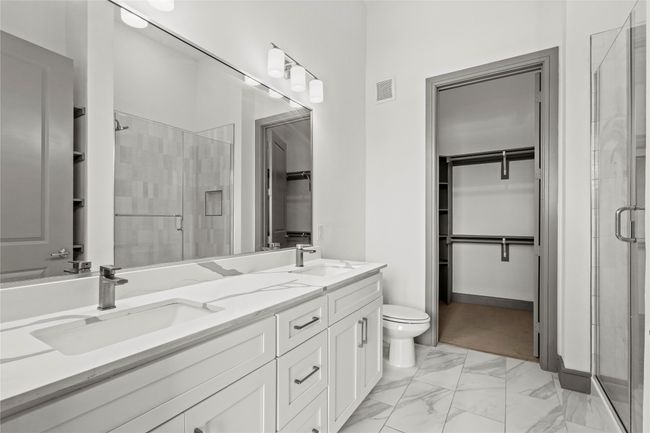 Bathroom with a spacious closet, a stall shower, double vanity, and toilet | Image 21