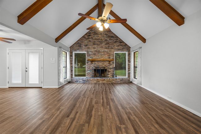 Unfurnished living room featuring a ceiling fan, plenty of natural light, baseboards, beam ceiling, and brick wall | Image 9