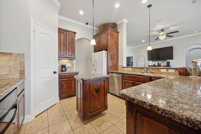 Kitchen with dishwasher, white fridge with ice dispenser, a sink, backsplash, and crown molding | Image 7