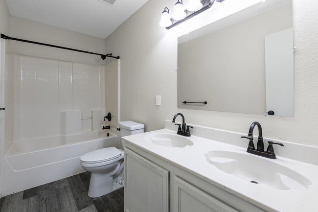 Bathroom featuring wood finished floors, double vanity, and shower / tub combination | Image 13