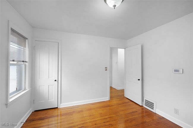 Unfurnished bedroom with wood finished floors, visible vents, and baseboards | Image 13