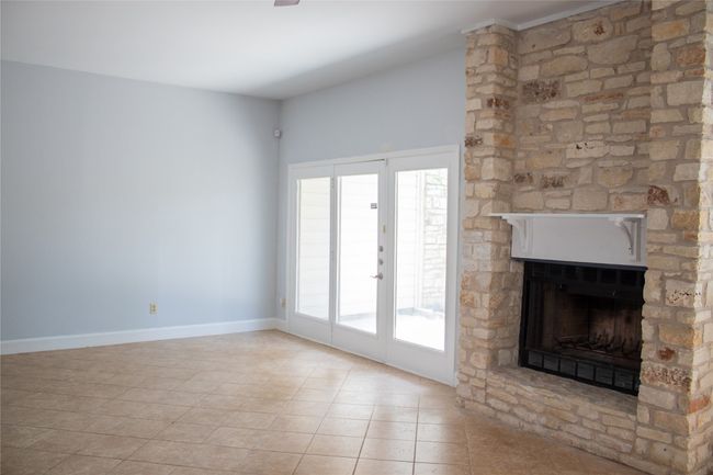 Unfurnished living room featuring baseboards, tile patterned flooring, and a stone fireplace | Image 11