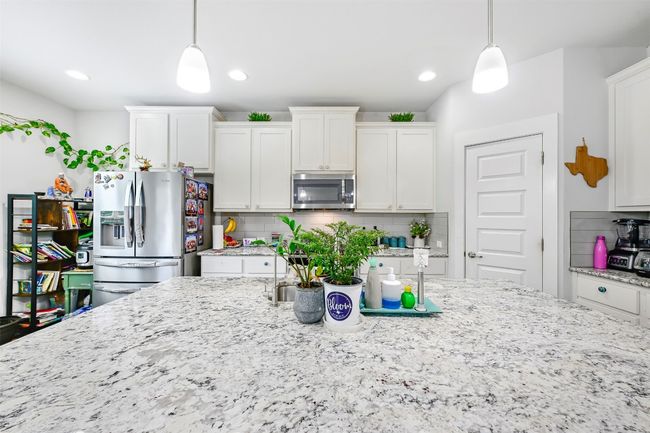 Kitchen featuring appliances with stainless steel finishes, white cabinets, tasteful backsplash, light stone countertops, and recessed lighting | Image 9