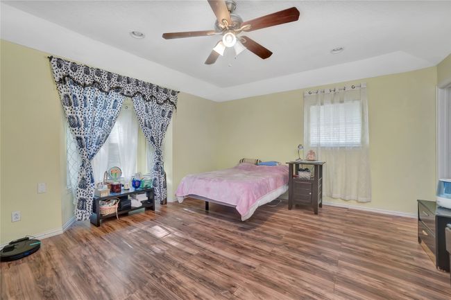 Bedroom featuring multiple windows, baseboards, wood finished floors, and recessed lighting | Image 16