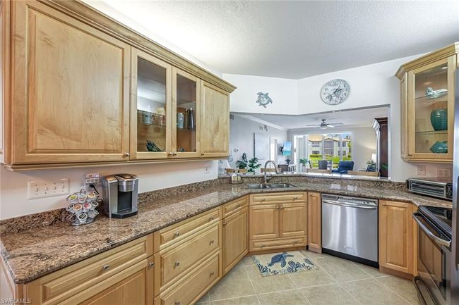 Kitchen featuring appliances with stainless steel finishes, dark stone countertops, light tile patterned floors, ceiling fan, and ornamental molding | Image 6
