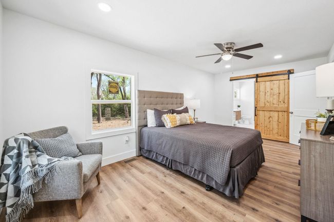 Bedroom with ceiling fan, recessed lighting, a barn door, light wood finished floors, and baseboards | Image 15