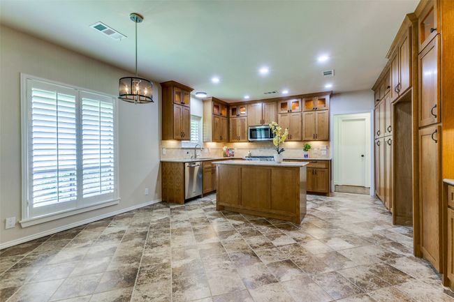 This kitchen is just lovely! So many cabinets with pull-out shelving in many, glass fronts on the upper, lighted cabinets and a moveable island. | Image 8