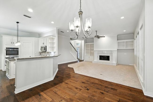 Kitchen with stainless steel appliances, a ceiling fan, open shelves, ornamental molding, and a tile fireplace | Image 9