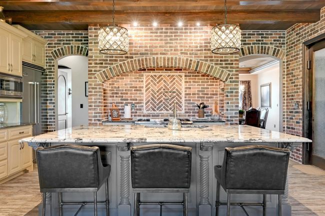 Kitchen with arched walkways, beam ceiling, stainless steel appliances, light wood-style flooring, and cream cabinets | Image 17