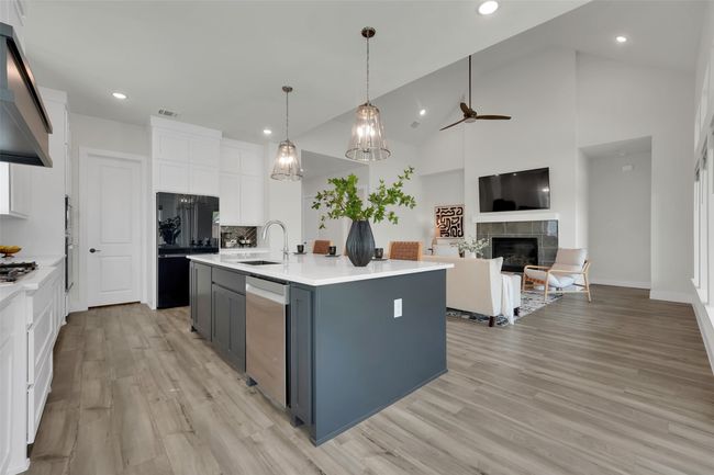 Kitchen with white cabinets, stainless steel appliances, a ceiling fan, under cabinet range hood, and a fireplace | Image 12