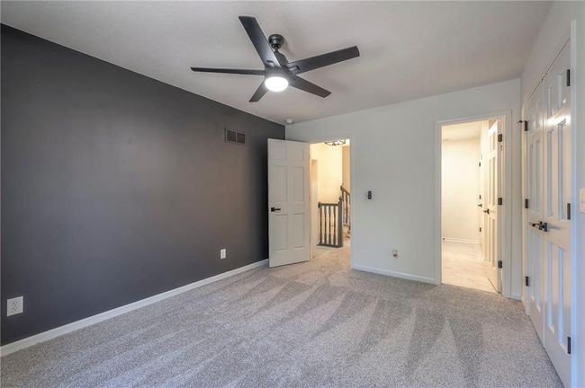 Unfurnished bedroom featuring carpet floors, ensuite bath, and ceiling fan | Image 11