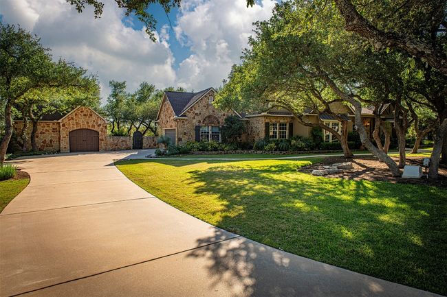 View of front of home featuring stone siding, a front lawn, concrete driveway, and a garage | Image 4