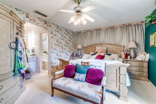 Bedroom featuring arched walkways, light carpet, ensuite bath, wallpapered walls, and ceiling fan | Image 14
