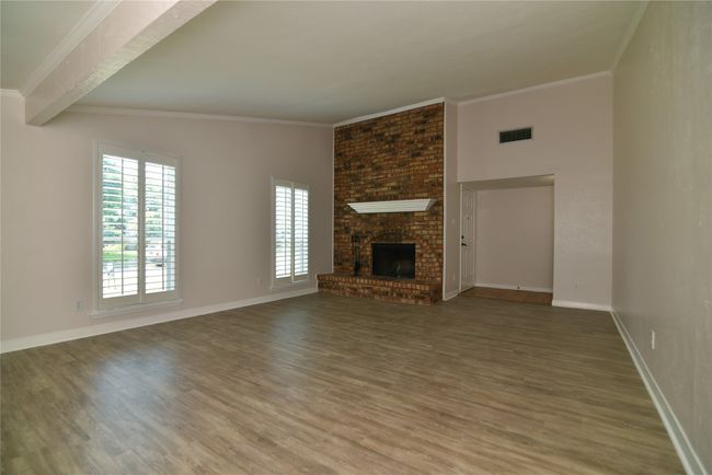 Unfurnished living room with wood finished floors, crown molding, baseboards, and a fireplace | Image 5