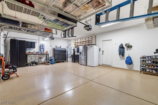 Garage featuring gas water heater, a garage door opener, and stainless steel fridge with ice dispenser | Image 37
