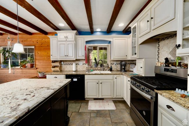 Kitchen with gas stove, black dishwasher, tasteful backsplash, beamed ceiling, and dark stone finish flooring | Image 15