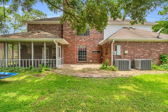 Back of the home has a screened porch and a patio area nestled under the shade. | Image 34