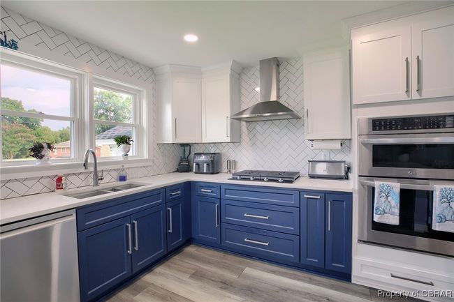 Kitchen with white cabinetry, sink, wall chimney exhaust hood, light hardwood / wood-style flooring, and appliances with stainless steel finishes | Image 37