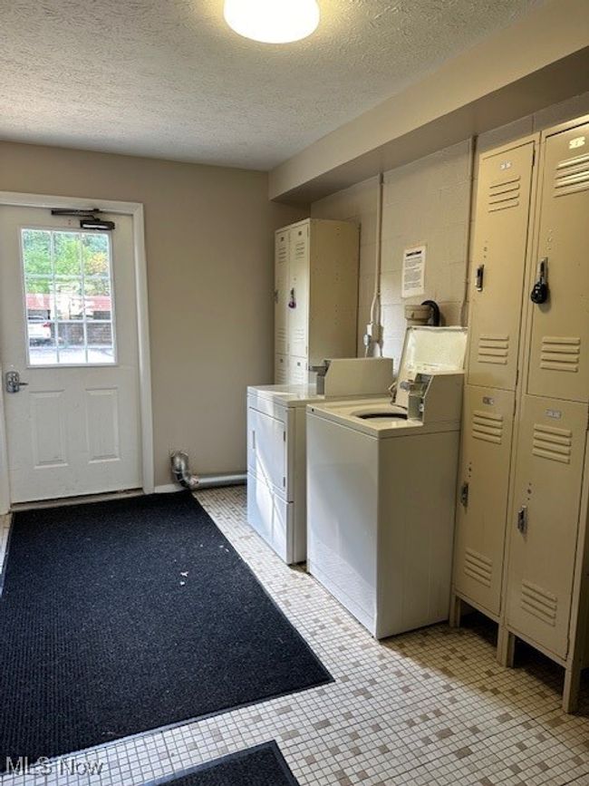 Clothes washing area with a textured ceiling, light tile patterned floors, and washing machine and dryer | Image 20