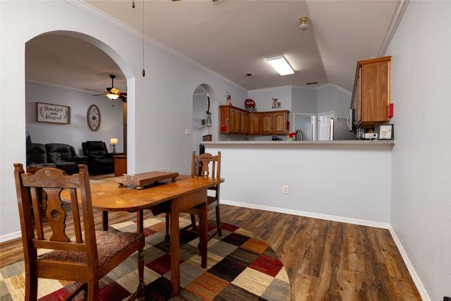 Dining area featuring arched walkways, dark wood-style flooring, ornamental molding, and ceiling fan | Image 14