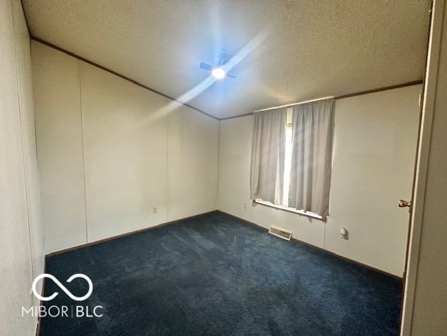 empty room featuring dark colored carpet, visible vents, and a textured ceiling | Image 15