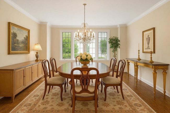 Dining area with crown molding, wood finished floors, baseboards, and a chandelier | Image 6