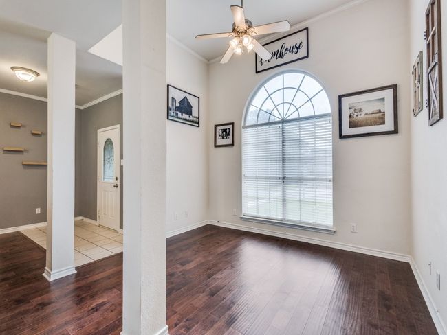 Empty room with a ceiling fan, wood-type flooring, crown molding, and baseboards | Image 4