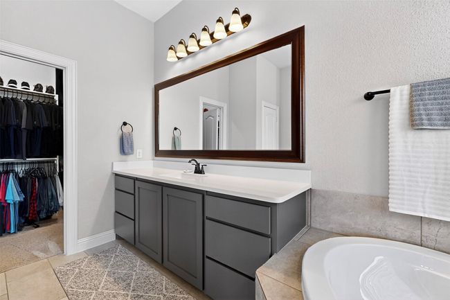 Bathroom with vanity, a bath, a walk in closet, and tile patterned flooring | Image 15