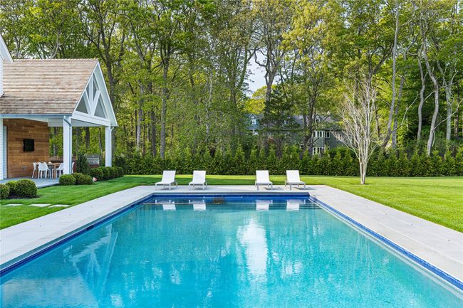 Swimming pool with a patio area, a lawn, and view of scattered trees | Image 46
