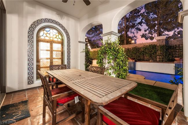 Outdoor dining in the loggia, view of the pool, ceiling fan and decorative window into the office. | Image 19