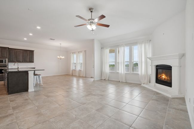 Unfurnished living room with a glass covered fireplace, plenty of natural light, a chandelier, a ceiling fan, and recessed lighting | Image 11