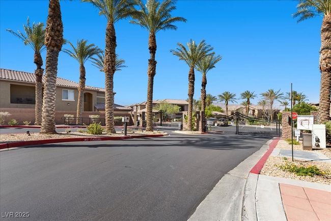 View of asphalt road with a gate, sidewalks, curbs, a gated entry, and traffic signs | Image 41