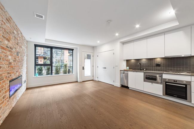 Kitchen with stainless steel appliances, white cabinets, wood finished floors, modern cabinets, and tasteful backsplash | Image 19