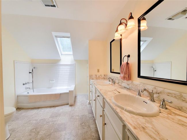 Spacious upstairs bathroom featuring a skylight, double sinks, granite countertops, and elegant tile flooring. | Image 26