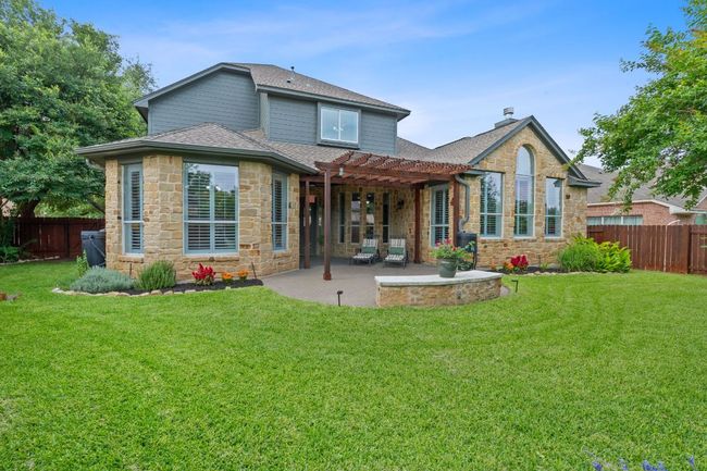 Back of property featuring a pergola, stone siding, a shingled roof, and a patio | Image 22