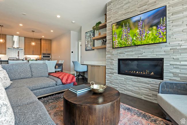 Living area with baseboards, a stone fireplace, wood finished floors, and recessed lighting | Image 7