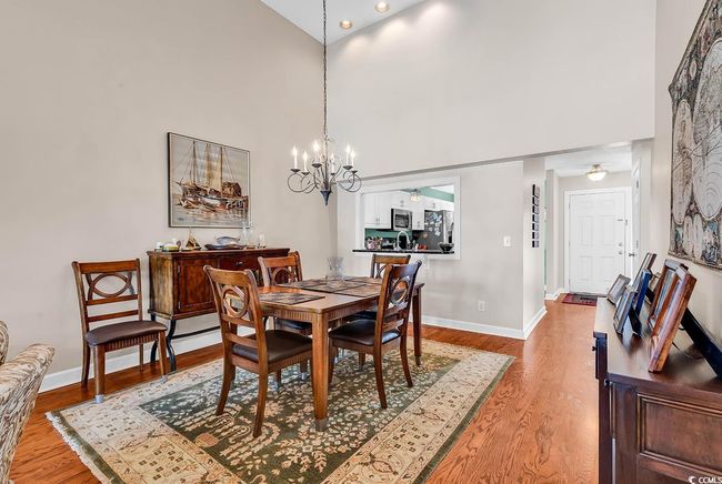 Dining room featuring a high ceiling, a chandelier, light wood finished floors, and baseboards | Image 7