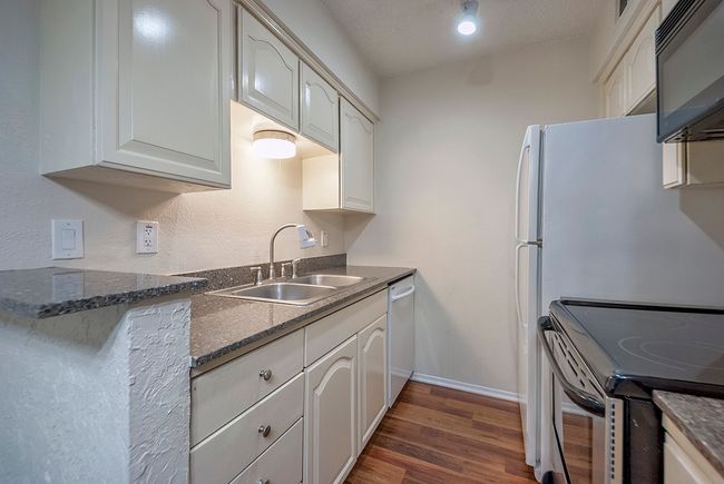 A bright kitchen with essential appliances: a dual sink, range and refrigerator, perfect for culinary adventures. | Image 14