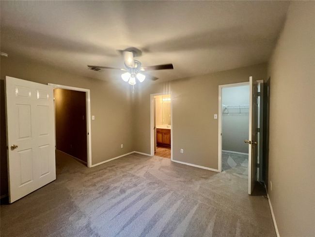 Unfurnished bedroom featuring a walk in closet, carpet flooring, connected bathroom, and ceiling fan | Image 30