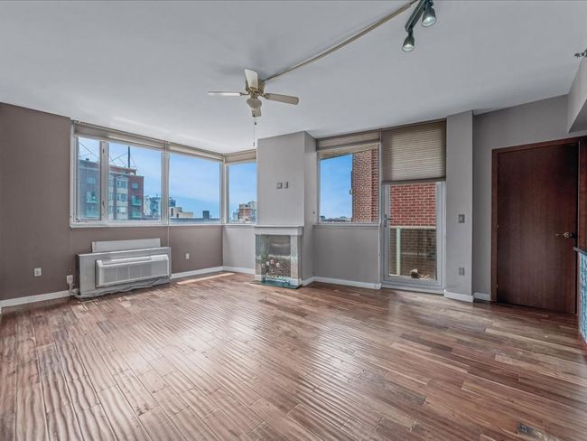 Unfurnished living room featuring a ceiling fan, a view of skyline, and wood finished floors | Image 7