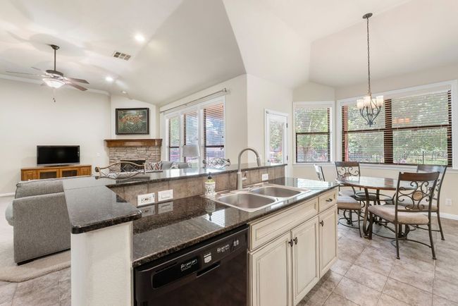 Kitchen featuring dishwasher, vaulted ceiling, open floor plan, a kitchen island with sink, and a fireplace | Image 11