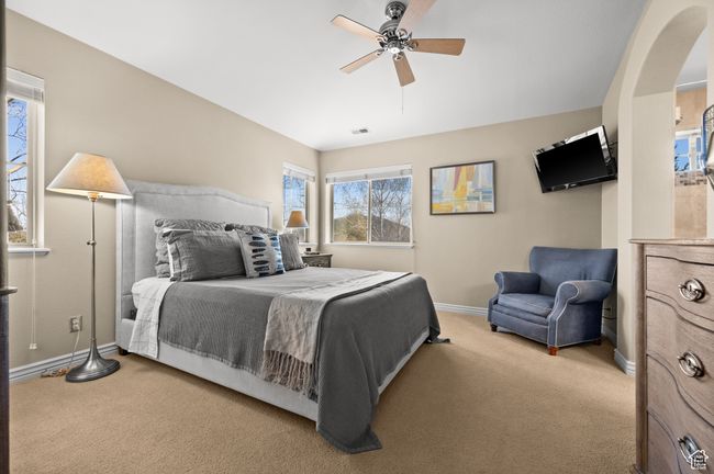 Bedroom with arched walkways, light colored carpet, and ceiling fan | Image 19