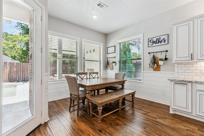 The kitchen opens directly into a generously sized breakfast room, featuring shiplap wainscoting and large windows that provide lovely backyard views. | Image 17